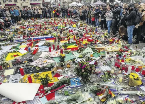  ?? PHILIPPE HUGUEN / AFP / GETTY IMAGES ?? People gather Thursday at the Place de la Bourse in Brussels to pay tribute to the victims of the bombings.