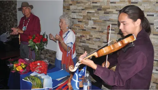  ?? Photos by Matthew Liebenberg ?? Métis fiddler Tristen Durocher from Buffalo Narrows performs during the book launch. Standing at the back are Métis elder Cecile Blanke and Joseph Naytowhow, who did honour songs at the event.