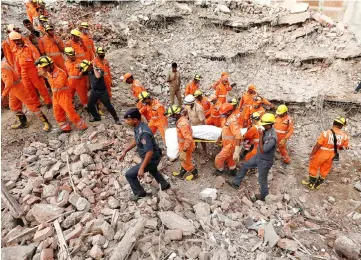  ??  ?? Rescue workers carry the body of a victim at the site of a collapsed residentia­l building at Shah Beri village in Greater Noida, India. — Reuters photo