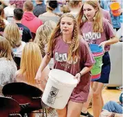 ??  ?? Students walk among classmates, parents and guests at Edmond Memorial High School, seeking last-minute donations at the final assembly for the school’s fundraisin­g effort dubbed Swine Week.