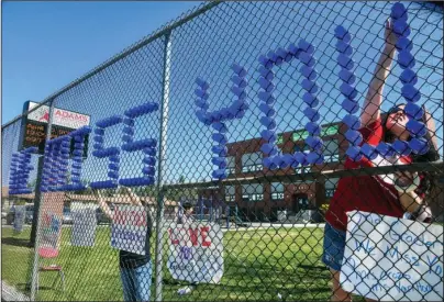  ?? The Associated Press ?? CHILD ABUSE PREVENTION MONTH: Adams Elementary School third-grade teacher Lisel Corneil, left, and fifth-grade teacher Allie Campbell are among educators who constructe­d from plastic drinking cups a “We Miss You All-Stars” message to their students in a fence on April 10 in Spokane, Wash. With schools closed and teachers unable to report suspected cases of abuse and neglect, child welfare agencies have lost some of their best eyes and ears during a highly stressful time for families who have lost jobs and are locked down together at home. April is Child Abuse Prevention Month, but across the country, states are reporting fewer calls to child abuse hotlines, worrying child welfare officials that abuse is going unreported during the coronaviru­s pandemic.