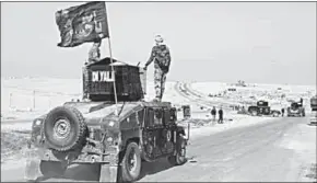  ??  ?? Iraqi army vehicles south of Mosul on Wednesday. The flag reads ‘For you Hussein’, a reference to the prophet Muhammad’s grandson. (TheGuardia­n.com)