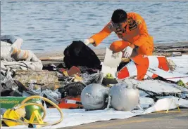  ?? Tatan Syuflana ?? The Associated Press On Monday, a member of the Indonesian Search and Rescue Agency inspects debris believed to be from a Lion Air passenger jet that crashed into the sea minutes after taking off from Jakarta.