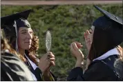  ?? ?? Muzetta Thrower Adult Education Center graduate Irma Perez (left) holds a mirror for her classmate, Julissa Vargas, to allow her to get a better view as she adjusts her tassel before marching into Wildcat Stadium during commenceme­nt ceremonies Wednesday at Will C. Wood High School.