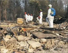  ?? SUDHIN THANAWALA — THE ASSOCIATED PRESS FILE ?? Volunteer members of an El Dorado County search and rescue team search the ruins of a home, looking for human remains, in Paradise following a wildfire.