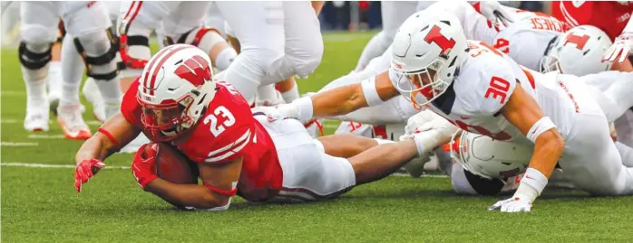  ?? AP ?? Wisconsin’s Jonathan Taylor (brought down by defensive back Sydney Brown in the first half) burned Illinois for 159 yards on 27 carries. The Badgers rushed for 357 yards and had a 15-minute advantage in time of possession.