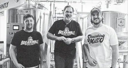  ?? LAURA BARTON THE WELLAND TRIBUNE ?? Fred Davies, centre, owner of Breakwall Brewing Co. in Port Colborne, stands with Cameron Sheddon, head brewer, left, and Conrad Davies, head of marketing and sales, in front of the in-house brewing distillery, where various kinds of local craft beer...