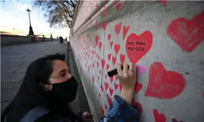  ?? Photograph: Andy Rain/EPA ?? A volunteer paint hearts on the National Covid Memorial Wall on the Embankment in central London.