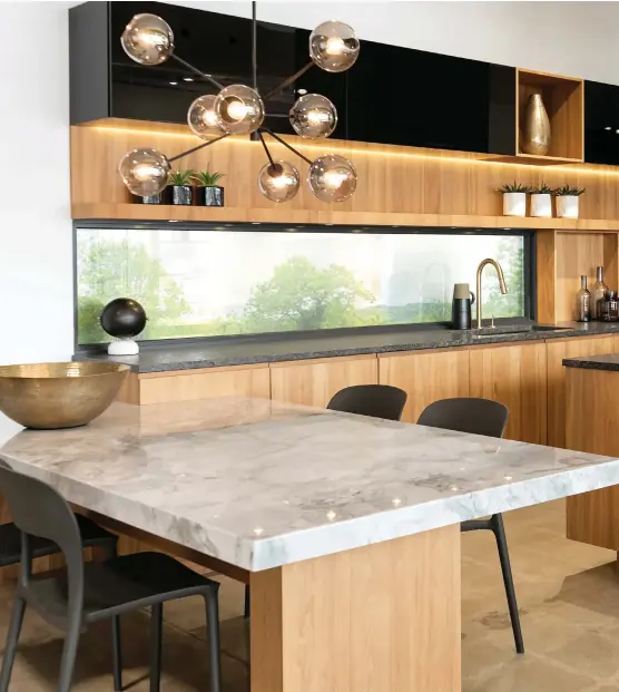  ??  ?? La table à manger ancrée au mur fait partie intégrante de la rénovation de cette cuisine. Les clients ont jeté leur dévolu sur ce luminaire spectacula­ire dont les rondeurs contrasten­t avec les lignes droites du décor.