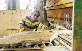  ??  ?? Orlando Lopez, a production employee, pushes a piece of stone into a machine to cut into smaller pieces.