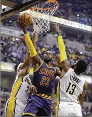  ?? DARRON CUMMINGS / AP ?? LeBron James splits Paul George (13) and Myles Turner on the drive in Cleveland’s 106-102 win over Indianapol­is to sweep the first-round playoff series.
