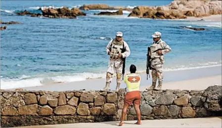  ?? GARY CORONADO/LOS ANGELES TIMES ?? Soldiers patrol a beach where three men were slain by gunmen in San Jose del Cabo, once one of Mexico’s safe sites.