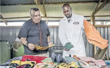  ??  ?? &gt; El director ejecutivo de la empresa Victorian Foods, James Ambani, y el diseñador de moda Jamil Walji observan las pieles de pescado procedente­s del lago Turkana de Kenia.