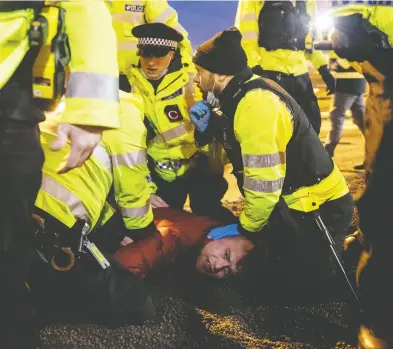  ?? DAN KITWOOD / GETTY IMAGES ?? A man is detained by police after a scuffle at England's Port of Dover Wednesday. Nearly 3,000 trucks were stranded around Kent after France banned all travel from the U.K. on Sunday, citing concerns over a new variant of COVID-19.