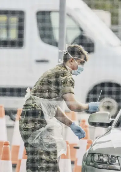  ??  ?? 0 Military personnel test essential workers at a drive-through coronaviru­s test centre in a Glasgow