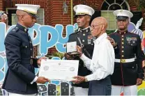  ?? Melissa Phillip / Staff photograph­er ?? Marine Capt. Ibrahim Diallo and Maj. Courtney Boston present Arthur Jackson, 99, with a replica Congressio­nal Gold Medal.