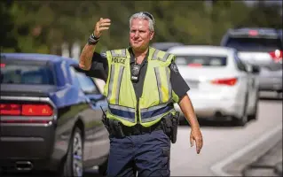  ?? ALLEN EYESTONE PHOTOS / THE PALM BEACH POST ?? Palm Beach County Schools officer Bob Keating is back to work directing traffic at the entrance to Wellington Landings Middle School. Last December, he was hit by a distracted driver while he was directing traffic and was seriously injured.