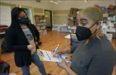  ?? Ted S. Warren/Associated Press ?? Kristin Travis, right, a community outreach doula, picks up home COVID-19 test kits Thursday from Stacey Silver in Seattle. On Friday, the number of U.S. deaths from COVID19 reached 900,000.