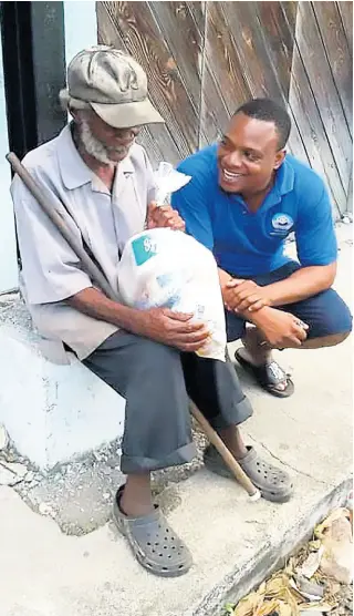  ?? PHOTO BY SHANNA MONTEITH ?? Ricardo Burke of the Yutes4Chan­ge charity group gifts toiletries to an elderly resident.