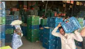  ??  ?? A worker carries a crate of tomatoes at Azadpur market.