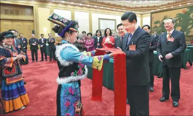  ?? LAN HONGGUANG / XINHUA ?? President Xi Jinping receives qianghong, a piece of silk used as a gift of greeting by the Qiang ethnic group, from an NPC deputy who is a member of the group as he joined a discussion with NPC deputies from Sichuan province on Wednesday in Beijing.