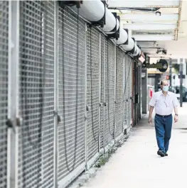  ?? MATIAS J. OCNER mocner@miamiheral­d.com ?? A man makes his way past shuttered storefront­s owned by Moishe Mana on Southeast First Street in downtown Miami.