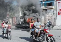  ?? ODELYN JOSEPH THE ASSOCIATED PRESS ?? Motorcycli­sts drive past burning tires set on fire to protest gas shortages in Port-au-Prince, Haiti, on Thursday.