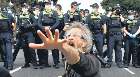  ??  ?? A protester confronts police during an anti-lockdown rally in Melbourne on Saturday.