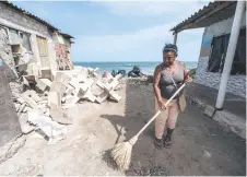  ?? ?? A woman sweeps outside her house affected by sea level rise in Tierra Bomba Island, Cartagena, Colombia.