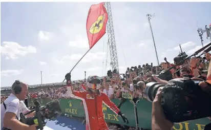  ?? FOTO: AP ?? Sebastian Vettel schwingt nach seinem Sieg in Silverston­e jubelnd die Ferrari-Fahne.