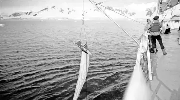  ?? — Reuters photo ?? Greenpeace activists Grant Oakes and Marcelo Legname pull a manta trawl out of the sea to collect water samples in Neko Harbour, Antarctica.