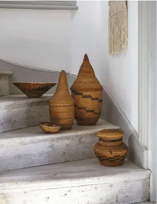  ??  ?? BELOW Any surface can become a focal point – this grouping of woven baskets creates an intriguing display on the stairs FACING PAGE Be con dent when playing with scale – gather different elements of tribal art such as masks, cushions and baskets, and...