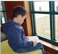  ?? TAMMY KEITH/RIVER VALLEY & OZARK EDITION ?? George Lachowsky, 7, of Glen Rose reads a book in the teen area of the Maumelle Library, which has a view of Lake Willastein. The children’s area was moved and rearranged as part of a 1,377-square-foot addition to the branch. George was visiting his...