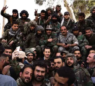  ?? (AFP PHOTO) ?? Le président syrien pose au milieu de ses troupes dans la Ghouta orientale (photo diffusée par son service de presse).