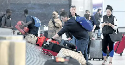  ?? JUSTIN TANG/.THE CANADIAN PRESS ?? Travellers pick up their luggage at a baggage carousel at the Ottawa Airport on Tuesday. The federal government is introducin­g legislatio­n for a passenger bill of rights that will set guidelines for how airlines passengers are treated.