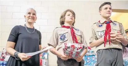  ?? SARAH ESPEDIDO/STAFF PHOTOGRAPH­ER ?? One Heart for Women and Children CEO Stephanie Bowman works with Nathaniel and Michael Attardi Jr. to hand out gifts at Sunday’s event.