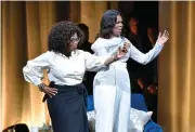  ?? AP PHOTO BY ROB GRABOWSKI ?? Michelle Obama, right, is greeted by Oprah Winfrey to discusses her new book during an intimate conversati­on to promote "Becoming" at the United Center on Tuesday, Nov. 13, in Chicago.