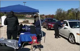  ?? CARMEN GUERRA ?? Volunteers work at a drive-thru flu shot event in Stenton, Pa., where they also distribute­d home test kits to detect possible signs of colon cancer.