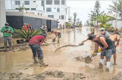  ?? ?? Lima. Varias personas ayudan a remover el lodo en una calle afectada por las lluvias recientes en esta capital.