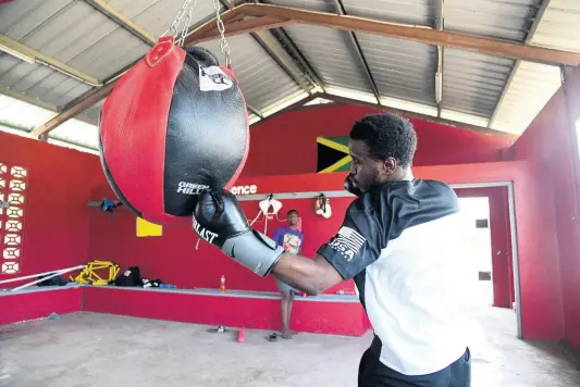  ?? PHOTOS BY GLADSTONE TAYLOR/MULTIMEDIA PHOTO EDITOR ?? Jiovani Hall goes to work on the wrecking ball heavy bag at Suga Knockout Boxing Gym at the Olympic Gardens Football Club in Kingston yesterday.