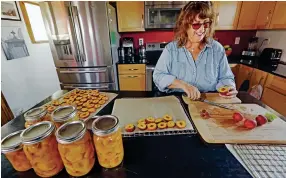  ?? PHOTOS BY
LUIS SÁNCHEZ SATURNO THE NEW MEXICAN ?? LEFT: Suzanne Chavez of Santa Fe slices peaches from her garden last month. She decided to retire early rather than returning to her job as a spa director during the pandemic. ‘My garden has never looked better,’ said Chavez, 61.