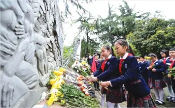  ??  ?? Students place flowers as they pay their respects to revolution­ary martyrs at a cemetery ahead of the annual Quingming festival, or Tomb Sweeping Day, in Hefel in Eastern China’s Anhui province on April 2