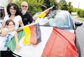  ?? Fotos: Marcus Merk ?? Mama Catarina Marschall-Brandoni hat ihren italienisc­hen Kleinwagen mit der Fahne Italiens geschmückt. Ehemann Jürgen und Tochter Laila halten zu Deutschlan­d.