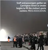  ?? PRESS ASSOCIATIO­N. ?? Staff and passengers gather on Carrington Street as smoke begins to fill the station’s porte cochère.