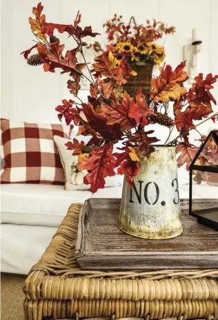  ??  ?? |LEFT| AUTUMN ACCESSORIE­S. Throw pillows and a galvanized container with leaves combine for a cozy fall look.
|BOTTOM|
FALLING SOFTLY. Jenny brought in the warmer colors of fall with pillows and large, cozy throws. The wall basket is filled to the brim with fall flowers and flanked by wall sconces. A woven trunk from IKEA completes the look.