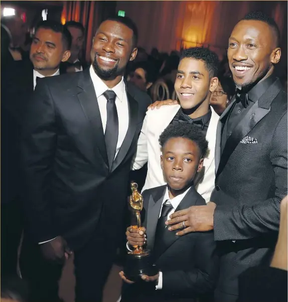  ??  ?? CAST MEMBERS Trevante Rhodes, left, Jharrel Jerome, Alex R. Hibbert (holding trophy) and supporting actor winner Mahershala Ali celebrate “Moonlight’s” big night at tthe Governors Ball. The coming-of-age film won three awards, including for best picture.