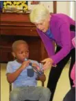  ?? MICHILEA PATTERSON — DIGITAL FIRST MEDIA ?? Candace Woessner, standing, helps a child learning to play the recorder during a free music program in Pottstown on Tuesday.