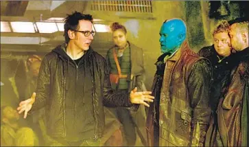  ?? Jay Maidment Marvel ?? JAMES GUNN, left, on the “Guardians of the Galaxy” set with Michael Rooker, with blue skin, and other members of the cast. Some fans as well as stars want to see him brought back for the franchise’s third movie.