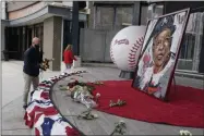  ?? JOHN BAZEMORE - THE ASSOCIATED PRESS ?? Atlanta Braves employees place flowers next to a portrait Atlanta Braves’ Hank Aaron outside Truist Park, Friday, Jan. 22, 2021, in Atlanta. Aaron, who endured racist threats with stoic dignity during his pursuit of Babe Ruth but went on to break the career home run record in the pre-steroids era, died peacefully in his sleep early Friday. He was 86.