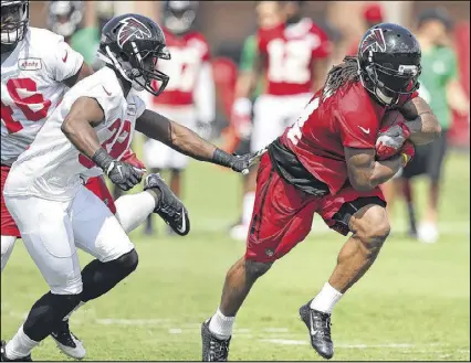  ?? CURTIS COMPTON / CCOMPTON@AJC.COM ?? Third-year running back Devonta Freeman, a Pro Bowler last season, breaks away from several would-be tacklers for yardage during a session at training camp on Friday.